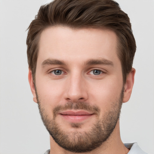 Joyful white young-adult male with short  brown hair and grey eyes