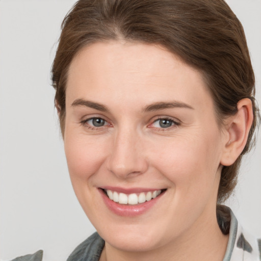 Joyful white young-adult female with medium  brown hair and grey eyes