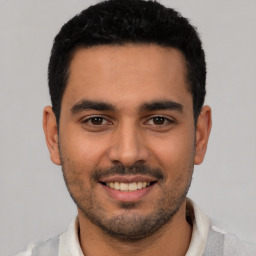 Joyful latino young-adult male with short  black hair and brown eyes