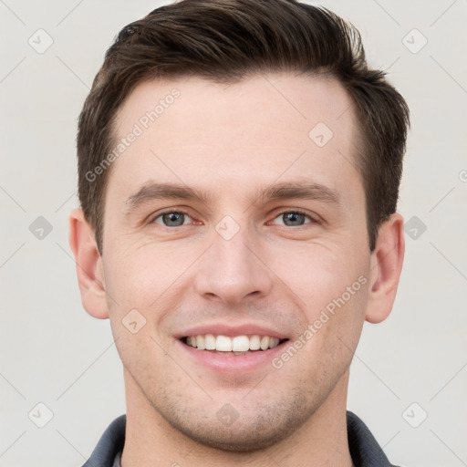 Joyful white young-adult male with short  brown hair and grey eyes