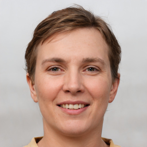 Joyful white young-adult female with short  brown hair and grey eyes