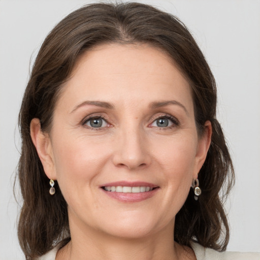 Joyful white adult female with medium  brown hair and grey eyes