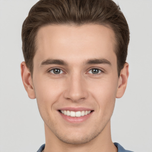 Joyful white young-adult male with short  brown hair and grey eyes