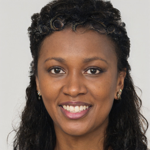 Joyful black young-adult female with long  brown hair and brown eyes