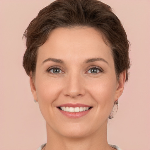 Joyful white young-adult female with short  brown hair and green eyes