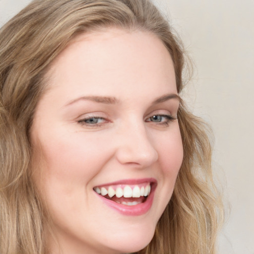 Joyful white young-adult female with long  brown hair and blue eyes