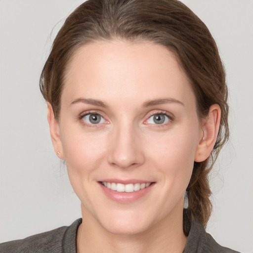 Joyful white young-adult female with medium  brown hair and grey eyes