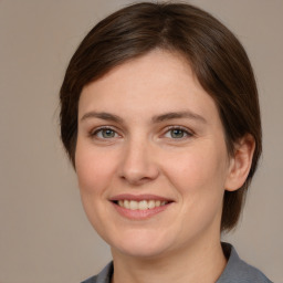 Joyful white young-adult female with medium  brown hair and grey eyes