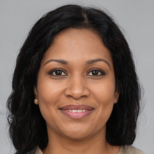 Joyful black adult female with long  brown hair and brown eyes