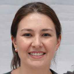 Joyful white young-adult female with medium  brown hair and grey eyes