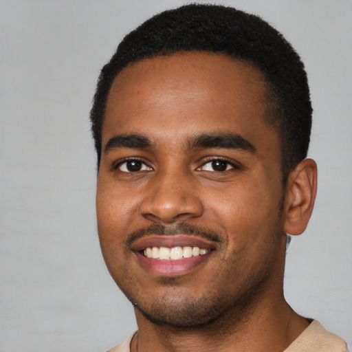 Joyful black young-adult male with short  black hair and brown eyes