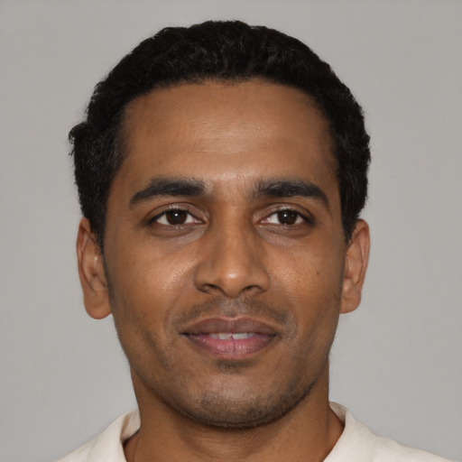 Joyful black young-adult male with short  black hair and brown eyes