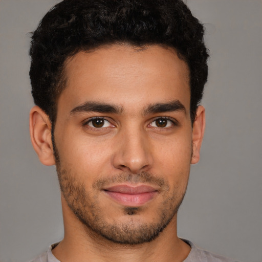 Joyful latino young-adult male with short  brown hair and brown eyes