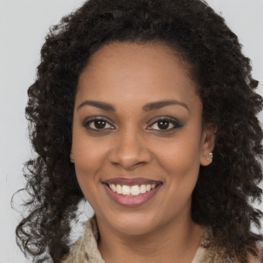 Joyful black young-adult female with long  brown hair and brown eyes