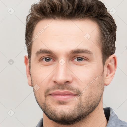 Joyful white young-adult male with short  brown hair and grey eyes