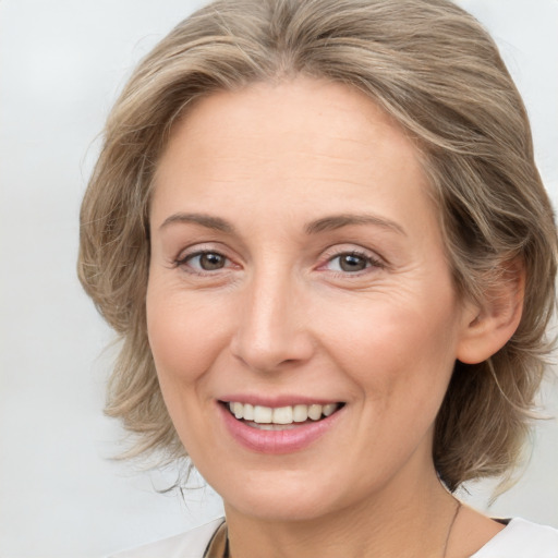 Joyful white adult female with medium  brown hair and grey eyes