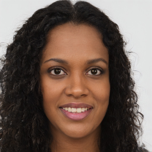 Joyful black young-adult female with long  brown hair and brown eyes