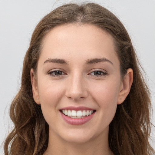 Joyful white young-adult female with long  brown hair and grey eyes