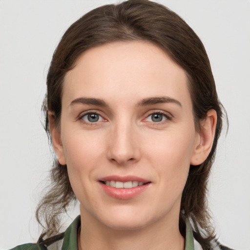 Joyful white young-adult female with medium  brown hair and green eyes