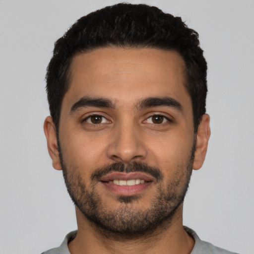 Joyful latino young-adult male with short  black hair and brown eyes