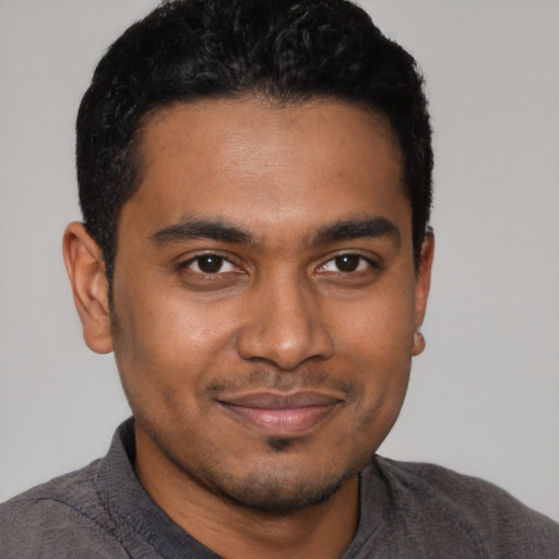 Joyful black young-adult male with short  brown hair and brown eyes