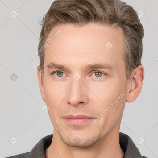 Joyful white young-adult male with short  brown hair and grey eyes