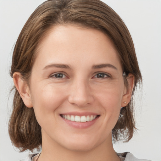 Joyful white young-adult female with medium  brown hair and grey eyes