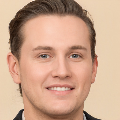 Joyful white young-adult male with short  brown hair and grey eyes