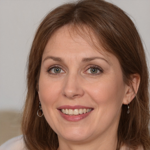 Joyful white adult female with long  brown hair and grey eyes