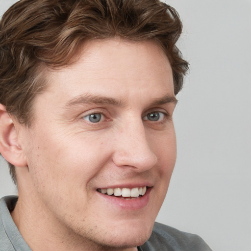 Joyful white young-adult male with short  brown hair and blue eyes