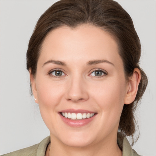 Joyful white young-adult female with medium  brown hair and grey eyes