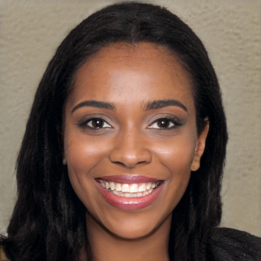 Joyful black young-adult female with long  black hair and brown eyes