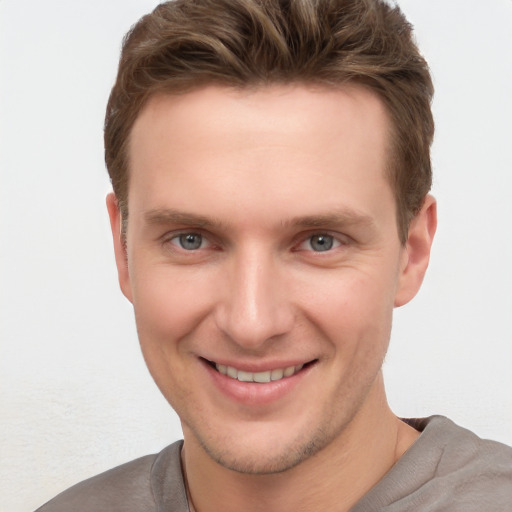 Joyful white young-adult male with short  brown hair and grey eyes