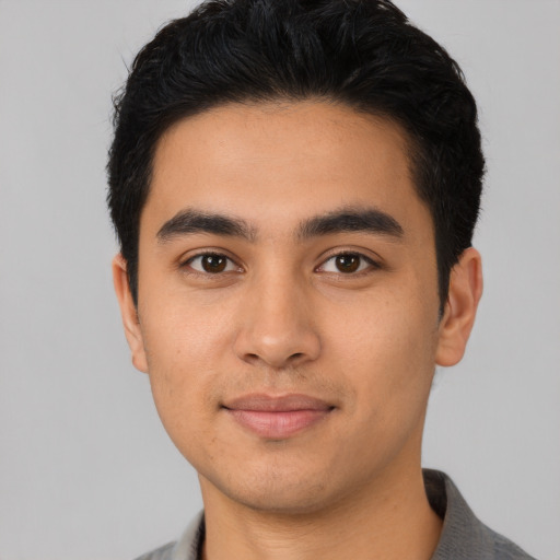 Joyful latino young-adult male with short  black hair and brown eyes