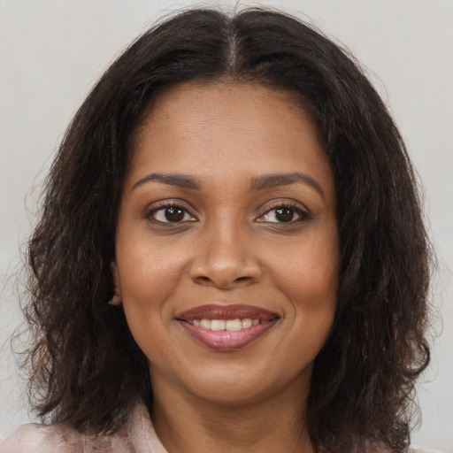 Joyful black young-adult female with long  brown hair and brown eyes