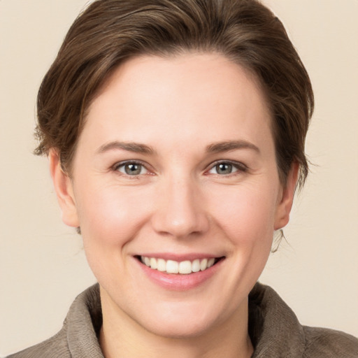 Joyful white young-adult female with short  brown hair and grey eyes