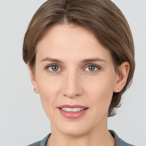 Joyful white young-adult female with medium  brown hair and grey eyes