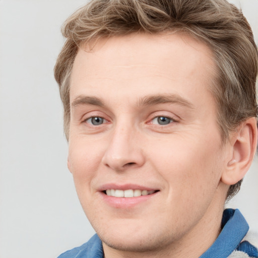 Joyful white young-adult male with short  brown hair and blue eyes