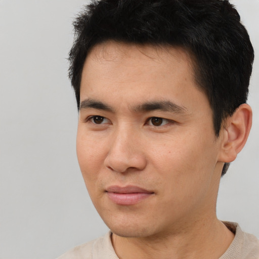 Joyful asian young-adult male with short  black hair and brown eyes