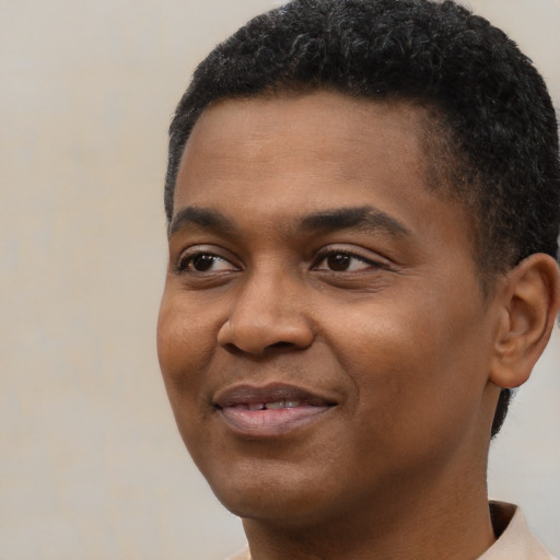 Joyful black young-adult male with short  black hair and brown eyes