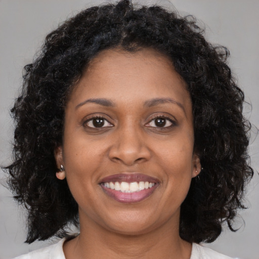 Joyful black young-adult female with long  brown hair and brown eyes