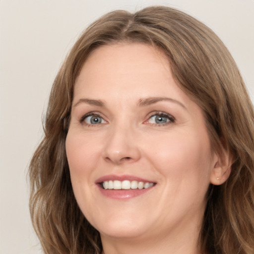 Joyful white adult female with long  brown hair and grey eyes