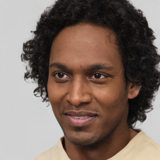 Joyful black young-adult male with short  brown hair and brown eyes