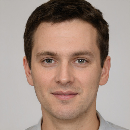 Joyful white young-adult male with short  brown hair and grey eyes