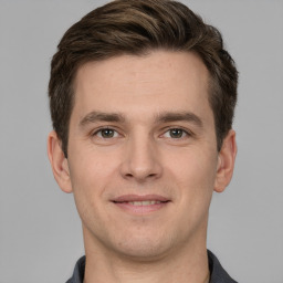 Joyful white young-adult male with short  brown hair and grey eyes