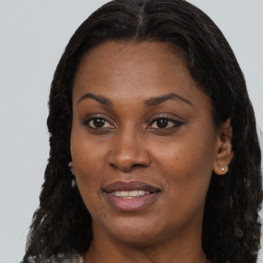 Joyful black young-adult female with long  brown hair and brown eyes