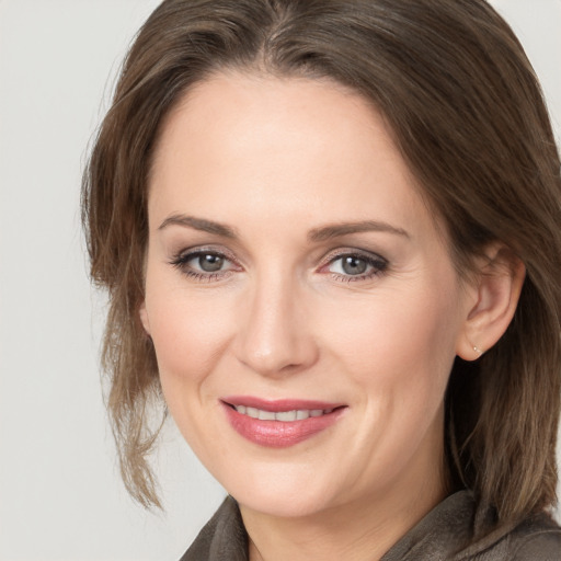 Joyful white young-adult female with medium  brown hair and grey eyes