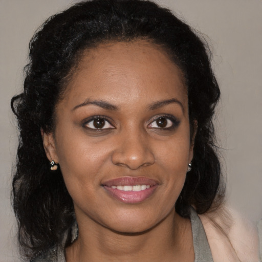 Joyful black young-adult female with long  brown hair and brown eyes