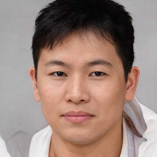 Joyful asian young-adult male with short  brown hair and brown eyes