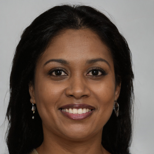 Joyful black young-adult female with long  brown hair and brown eyes